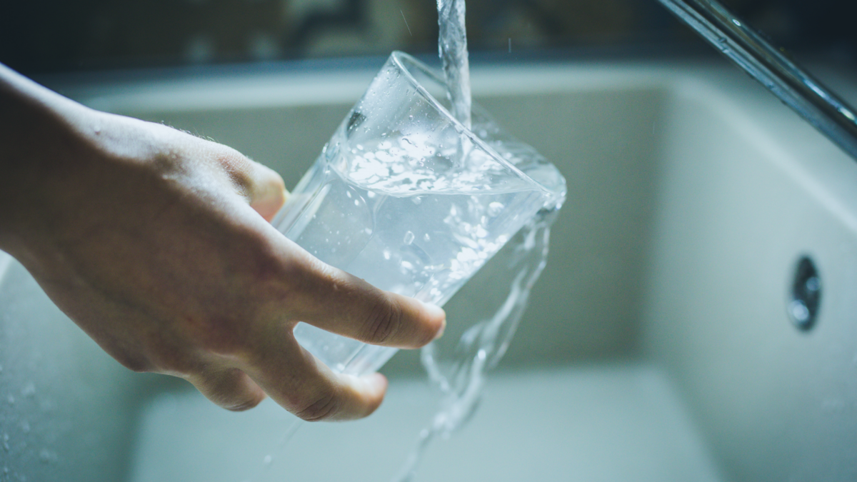 Filling up a glass of water using tap in kitchen sink.