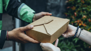Close up of a person delivering a food box to another person