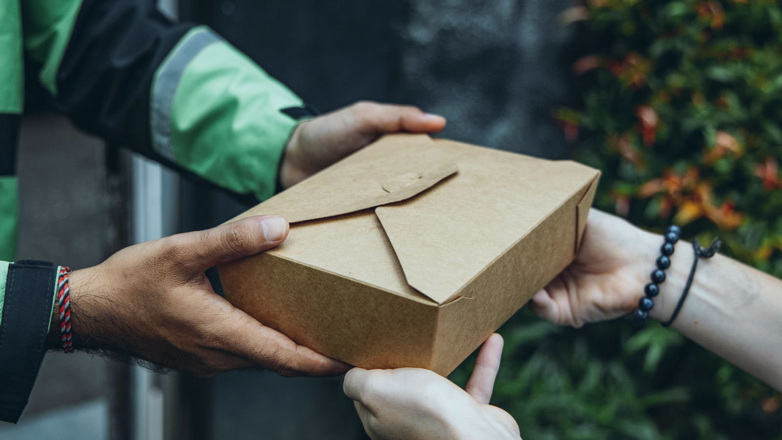 Close up of a person delivering a food box to another person